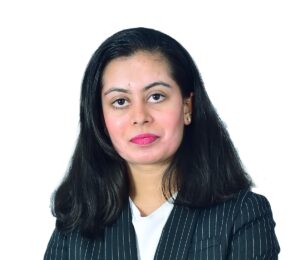 Porträt einer Frau mit schwarzen schulterlangen Haaren, gestreiftem Blazer und weißem Oberteil vor weißem Hintergrund.