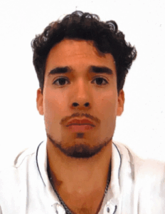 Porträt eines jungen Mannes mit dunklen lockigen Haaren und kurzem Bart vor weißem Hintergrund