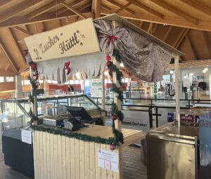 Zucker-Hüttl 3 Verkaufsstand Zucker-Hüttl mit Weihnachtsdekoration aus Girlanden und roten Ornamenten in einem Holzbau.